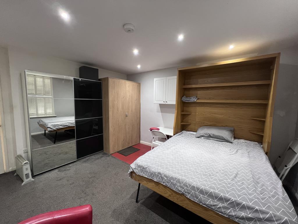 Lot: 23 - SIX-BEDROOM GUEST HOUSE - Ground floor studio room showing bed pulled out